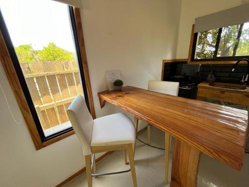 cocina con mesa de madera y sillas blancas en Studio Cabin I, en José Ignacio