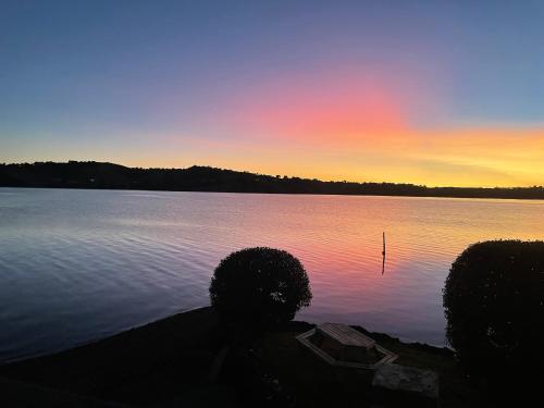 a sunset over a lake with a boat in the water at Breeze Inn in Parua Bay