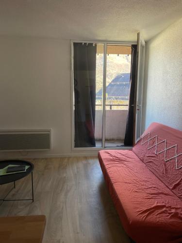 une chambre avec un lit rouge et une grande fenêtre dans l'établissement Studio vue sur Montagnes, à Laruns