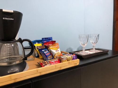 a counter with a blender and two glasses and snacks at Suíte Verão na Praia in Cabo Frio