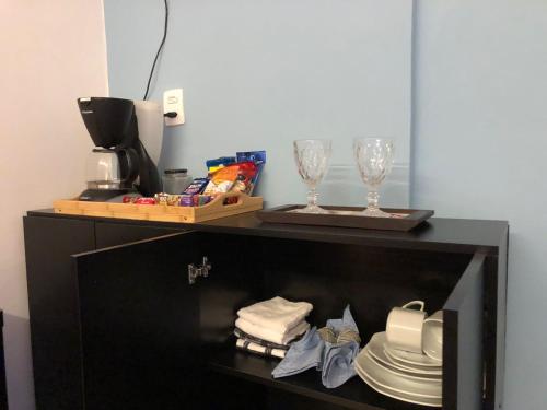 a shelf with two wine glasses and plates on it at Suíte Verão na Praia in Cabo Frio