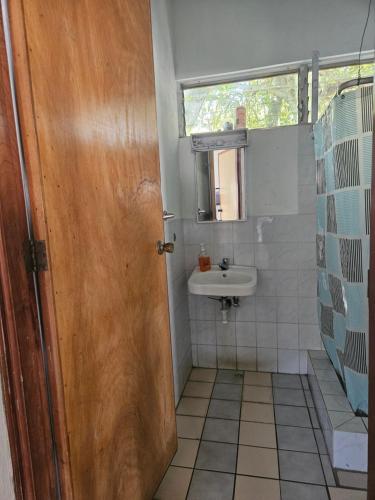 a bathroom with a sink and a wooden door at CHALET EN PUERTO VIEJO IZTAPA in Escuintla
