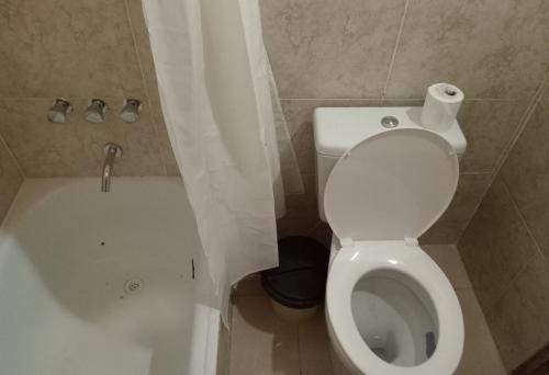 a bathroom with a white toilet and a bath tub at Casa de Campo Atenea in Santiago del Estero