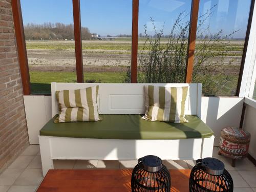 a white bench sitting in a room with a window at vrijstaande ruime familiewoning landelijk gelegen in Lewedorp