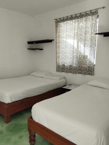 a room with two beds and a window withacers at Lunazul Eco-Cabaña Frente al Mar in Mahahual