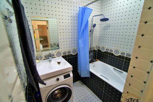 ein Badezimmer mit einem Waschbecken und einer Waschmaschine neben einer Badewanne in der Unterkunft Family 3-room apartment in Duschanbe