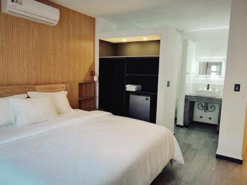 um quarto com uma grande cama branca e um lavatório em HOTEL BALUARTE BOUTIQUE PANAMA em Cidade do Panamá