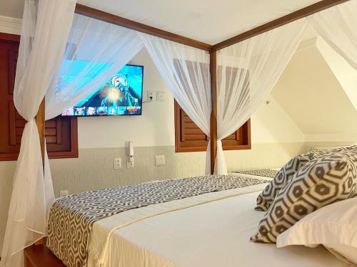 a bedroom with a bed with curtains and a tv at Mini Hotel Dunas in Jericoacoara