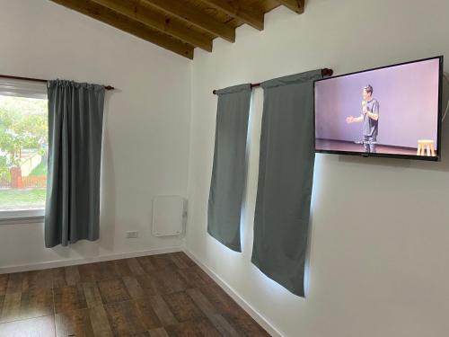 einen TV an der Wand in einem Zimmer mit Vorhängen in der Unterkunft Panchito. in San Clemente del Tuyú