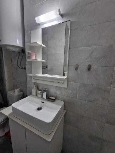 een badkamer met een witte wastafel en een spiegel bij Apartman Dixy in Pirot