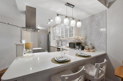 a kitchen with a white counter with chairs and a table at Skyview Executive Stay in Victoria
