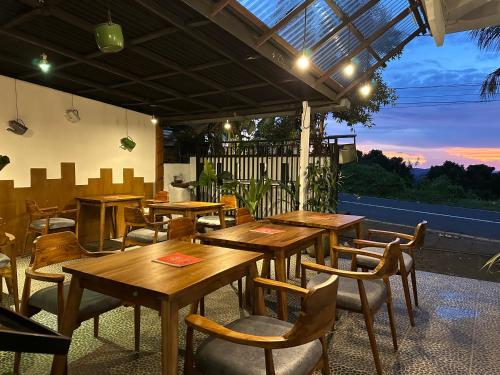 restauracja z drewnianymi stołami i krzesłami na patio w obiekcie Dong Paloh Hostel w mieście Munduk