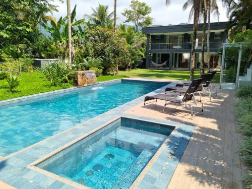 - une piscine avec 2 chaises à côté d'une maison dans l'établissement Paraiso em Angra dos Reis, à Angra dos Reis