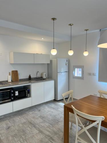 eine Küche mit weißen Schränken und einem Holztisch in der Unterkunft Casa de playa y sol in Monte Hermoso