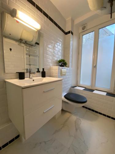 baño con lavabo y aseo y ventana en L'industriel en Ablis