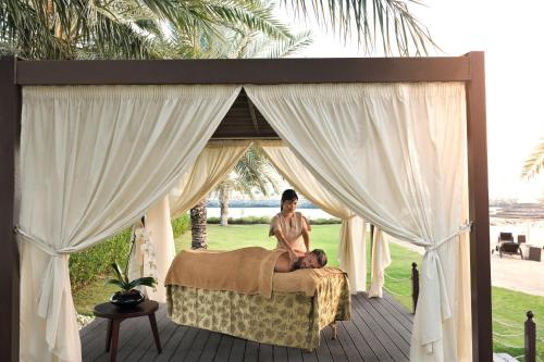 a woman sitting on a bed on a porch at InterContinental Abu Dhabi by IHG in Abu Dhabi