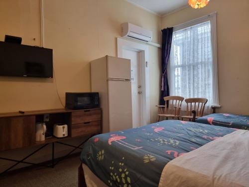 a room with a bed and a refrigerator and a window at Golden Cross Hotel in Waihi