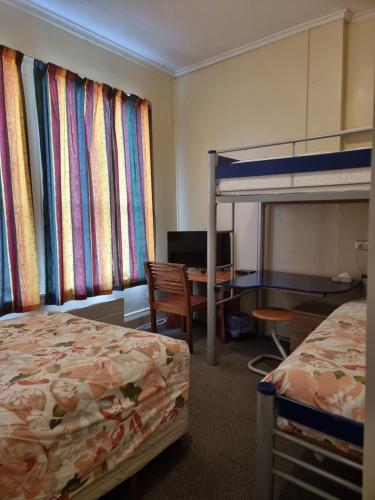 a hotel room with two beds and a desk and a bunk bed at Golden Cross Hotel in Waihi