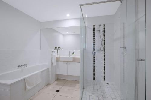 a white bathroom with a shower and a sink at Treetop Horizons - Experience Red Hills Local Vibe in Brisbane