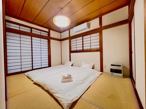 - une chambre avec un lit blanc dans une pièce dotée de fenêtres dans l'établissement 叶, à Nishikichō