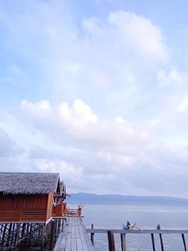 a wooden dock with a building on the water at Happy Homestay Arborek in Besir