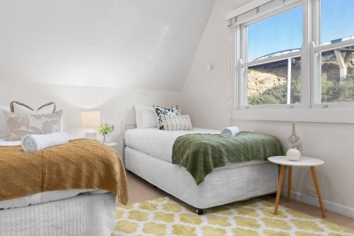 a white bedroom with a bed and a window at City Lights at the Hill - Newcastle Panoramas in Newcastle