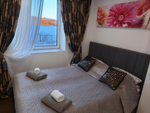 1 dormitorio con 1 cama con toallas y ventana en Bergen sunrise Apartment - self check in - Free Parking en Bergen