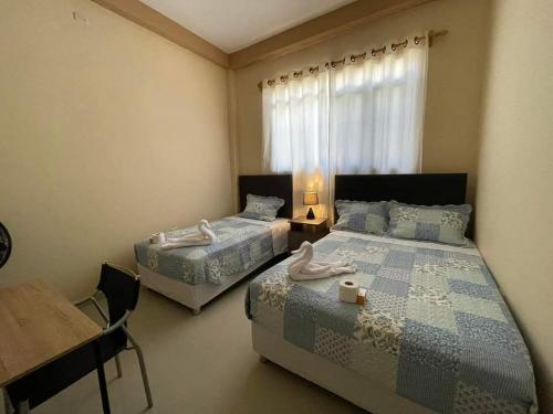 タララにあるLa Pequeña Suizaのベッドルーム1室(ベッド2台、テーブル、窓付)