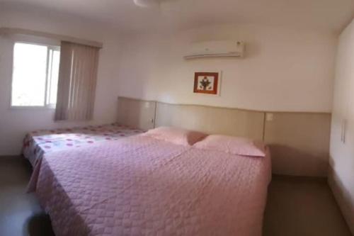 una camera da letto con un letto con lenzuola rosa e una finestra di Casa no Paraíso - Reserva Sapiranga Praia do Forte a Mata de Sao Joao