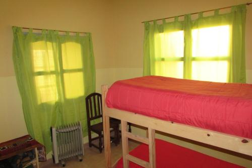 a bedroom with a bed with green and red curtains at Hostel Céntro Belén in Belén