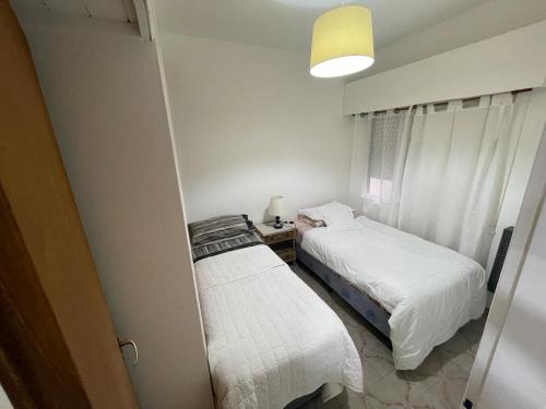 Duas camas num pequeno quarto com um candeeiro em en lo de Pancho 2 em Río Gallegos