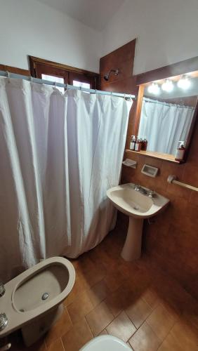 une salle de bain avec toilettes, lavabo et rideau de douche dans l'établissement Casa Rumipal, à Villa Rumipal