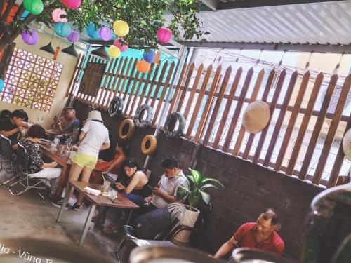 een groep mensen die aan tafels in een restaurant zitten bij Homestay GÁC MƠ Vũng Tàu in Vung Tau