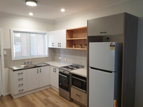 cocina con armarios blancos y nevera en Lisianna Apartments en Hervey Bay