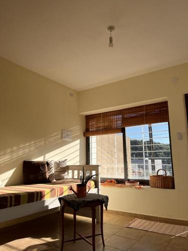 a bedroom with a bed and a table and a window at LA SERENA, Casa Serrana in Río Ceballos