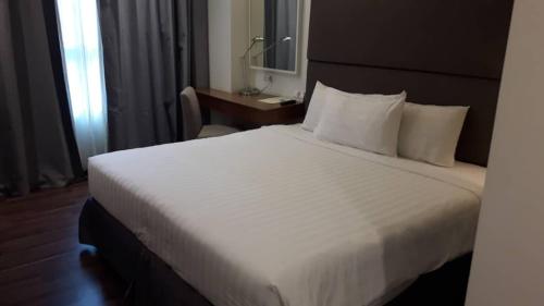 a bedroom with a large white bed with a desk at WP Hotel in Kuala Lumpur