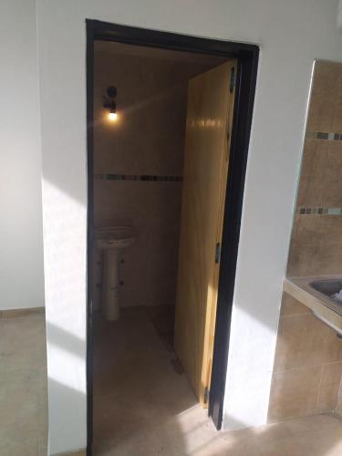 een badkamer met een deur naar een toilet bij La celebración in Francisco Álvarez