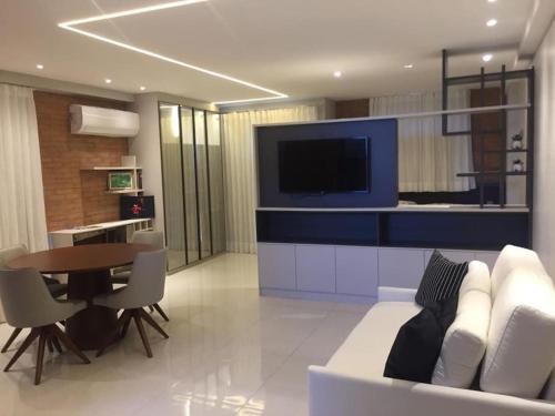 a living room with a white couch and a table at Flat novo e estiloso na praia Ponta de Campina in Cabedelo