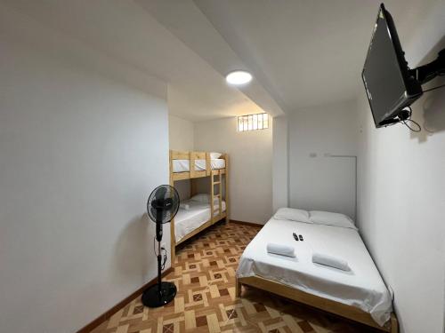 um pequeno quarto com uma cama e uma televisão em MIHAHI BEACH em Máncora