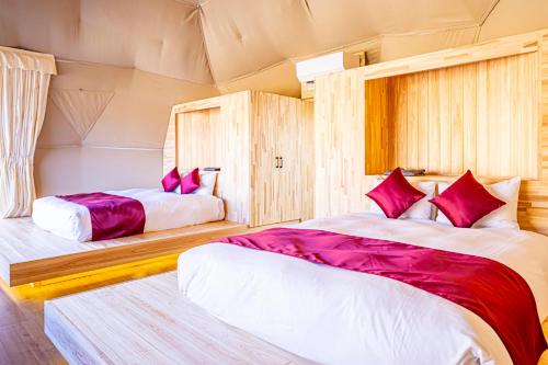 a bedroom with two beds with red pillows at glampark ACONCAGUA RESORTS in Minami Aso