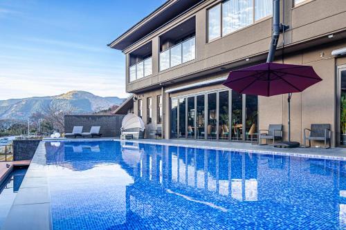 a swimming pool with an umbrella next to a building at glampark ACONCAGUA RESORTS in Minami Aso