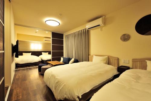 a hotel room with two beds and a couch at Rakuten STAY x Shamaison Osaka Dekijima Station in Osaka