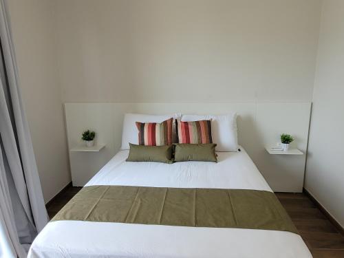a bedroom with a white bed with two pillows at Sobrado com garagem e churrasqueira in Tijucas