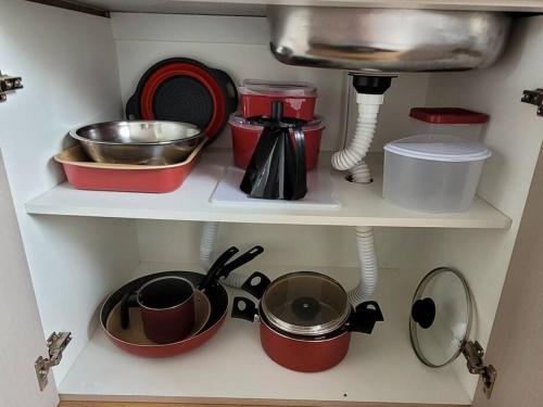 a kitchen shelf with pots and pans and a sink at Sobrado com garagem e churrasqueira in Tijucas