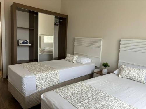 a bedroom with two beds and a mirror at Sobrado com garagem e churrasqueira in Tijucas
