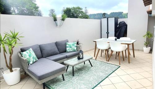 a patio with a couch and a table on a balcony at Penthouse Furnas in Furnas