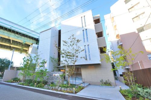 a white building with trees in front of it at Rakuten STAY x Shamaison Osaka Dekijima Station in Osaka