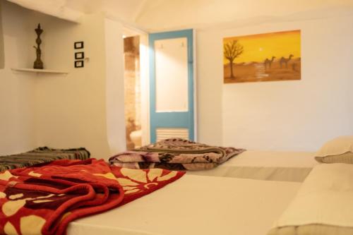 een slaapkamer met 2 bedden en een schilderij aan de muur bij Nubian Beach - حسن فوكس in Aswan