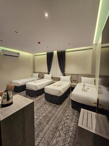 una habitación de hotel con 3 camas en una habitación en عقارات سلامة, en Zāwiyat Nābit