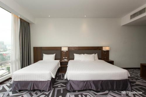 a hotel room with two beds and a window at WP Hotel in Kuala Lumpur